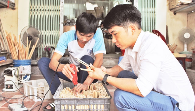 Nguyễn Văn Mão (người bên phải) kiểm tra chất lượng sản phẩm ống hút tre trước khi xuất khẩu.