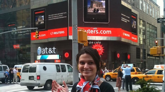 Alina Vandenberghe ở Quảng trường Thời đại (New York), đứng bên dưới quảng cáo cho ứng dụng Thomas Reuters iPad do cô thiết kế.