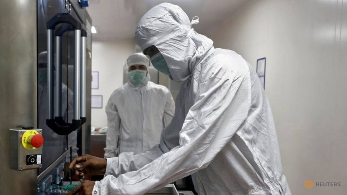 Một nhân viên y tế lấy các lọ vaccine Covishield khỏi máy kiểm tra trực quan bên trong phòng thí nghiệm tại Viện Huyết thanh Ấn Độ. Ảnh: Reuters
