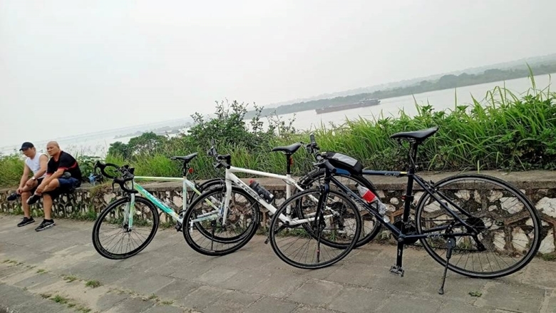  Du khách dừng chân tại đê sông Hồng khi trải nghiệm đạp xe quanh Hà Nội. (Ảnh: Vương Hà)