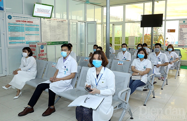 Bác sỹ và nhân viên y tế ngồi chờ đến lượt tiêm