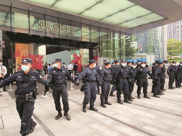Nhân viên an ninh tạo thành hàng rào trước trụ sở chính của China Evergrande, nơi nhiều người tập trung đòi nợ. Ảnh: Reuters 