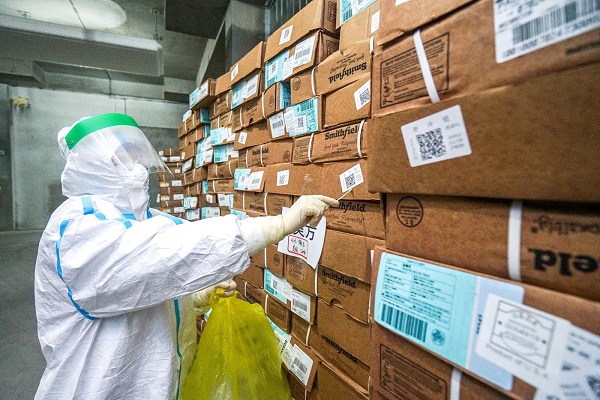 Một nhân viên y tế mặc đồ bảo hộ thu thập mẫu từ một gói thực phẩm đông lạnh nhập khẩu để xét nghiệm nhanh coronavirus tại một chợ bán buôn ở Trung Quốc.