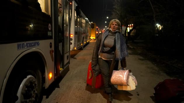 Một phụ nữ mang theo đồ đạc của mình khi những người sơ tán khỏi Cộng hòa Nhân dân Donetsk tự xưng ngồi trên xe buýt chờ được di dời.
