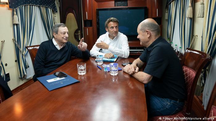 Tổng thống Pháp Emmanuel Macron (phải) bắt tay Thủ tướng Đức Olaf Scholz (giữa), bên cạnh là Thủ tướng Ý Mario Draghi, khi họ đi trên chuyến tàu tới Kyiv 