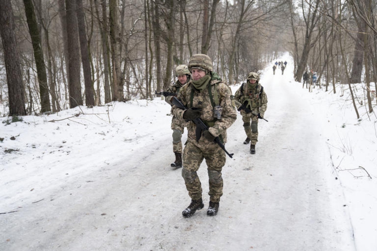 Các tình nguyện viên của Lực lượng Phòng vệ Lãnh thổ Ukraine đi qua một con đường phủ đầy tuyết trắng ở ngoại ô Kiev hồi đầu tháng 2. Ảnh: Washington Post