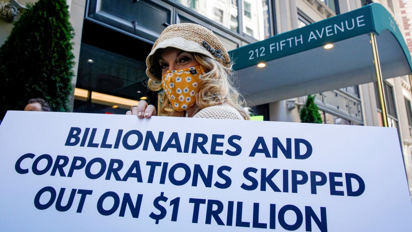 Một thành viên tổ chức Các triệu phú Yêu nước giơ bảng biểu tình bên ngoài căn hộ của tỉ phú Jeff Bezosp/REUTERS