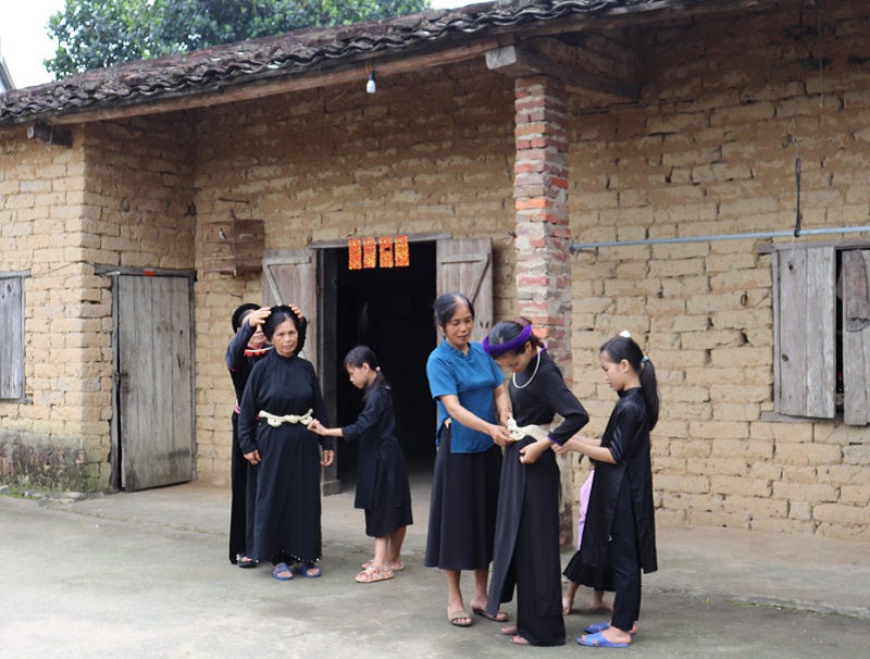 Người dân thôn Bản Cáu (xã Lục Hồn, huyện Bình Liêu) bên nếp nhà truyền thống (ảnh báo Quảng Ninh)