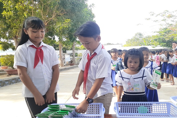 Các em học sinh thực hành gấp vỏ hộp sữa sau khi uống để dễ thu gom và tái chế.