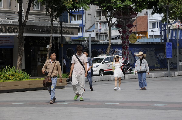 Một nhóm bạn trẻ người Việt Nam dạo chơi và chụp hình trên phố đi bộ Nguyễn Huệ cũng không đeo khẩu trang.