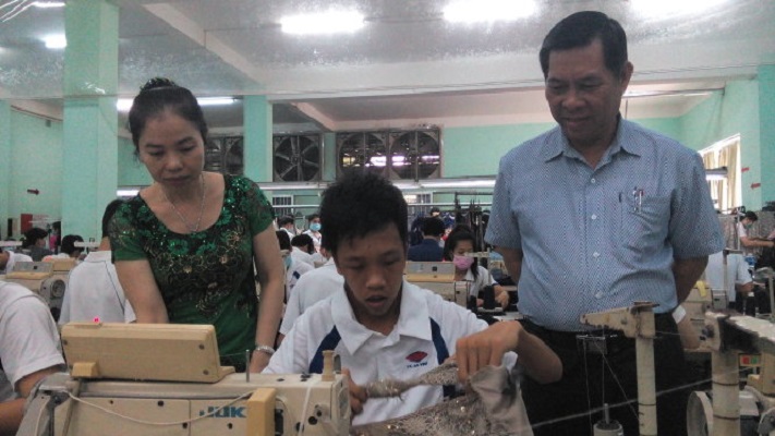 Ông Nguyễn Tấn Thanh và vợ hướng dẫn một học viên may bị di chứng chất độc màu da cam.