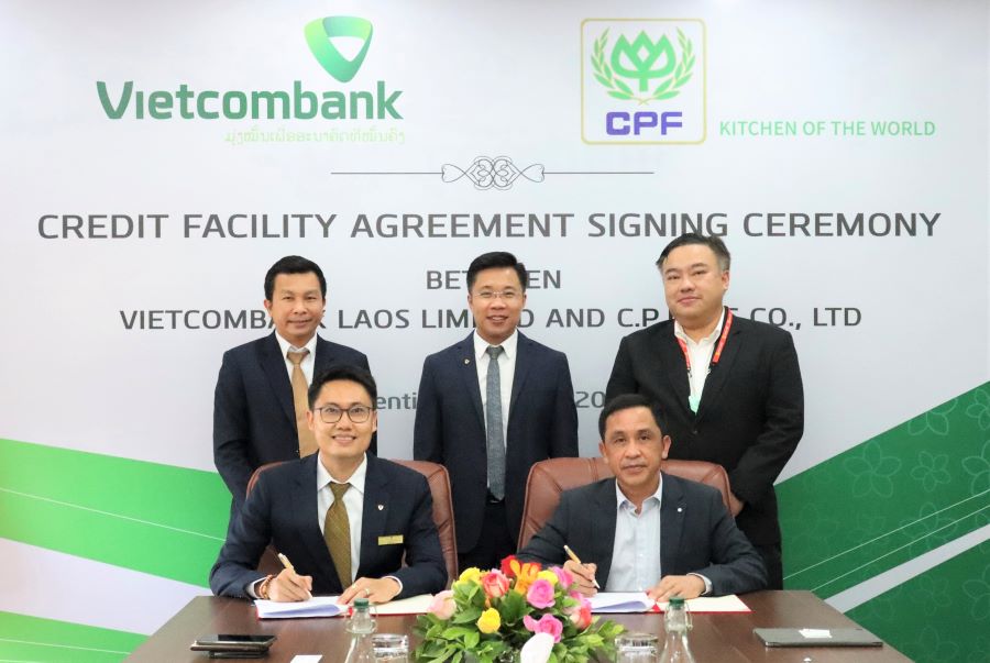 Ông Wiley Khotnhotha - Phó Tổng Giám đốc Vietcombank Lào (hàng đầu, bên trái) và ông Thamnong Pholthongmak - Chủ tịch CP Lào (hàng đầu, bên phải) thực hiện ký kết trước sự chứng kiến của đại diện lãnh đạo hai bên