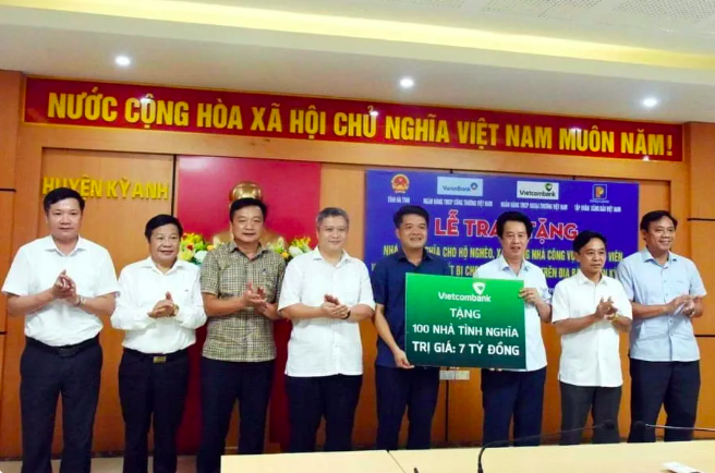 Ông Nguyễn Mỹ Hào - UV BTV Đảng ủy, Thành viên HĐQT Vietcombank (thứ 3, từ phải sang) trao biểu trưng hỗ trợ kinh phí xây dựng 100 căn nhà tình nghĩa tổng trị giá 7 tỷ đồng