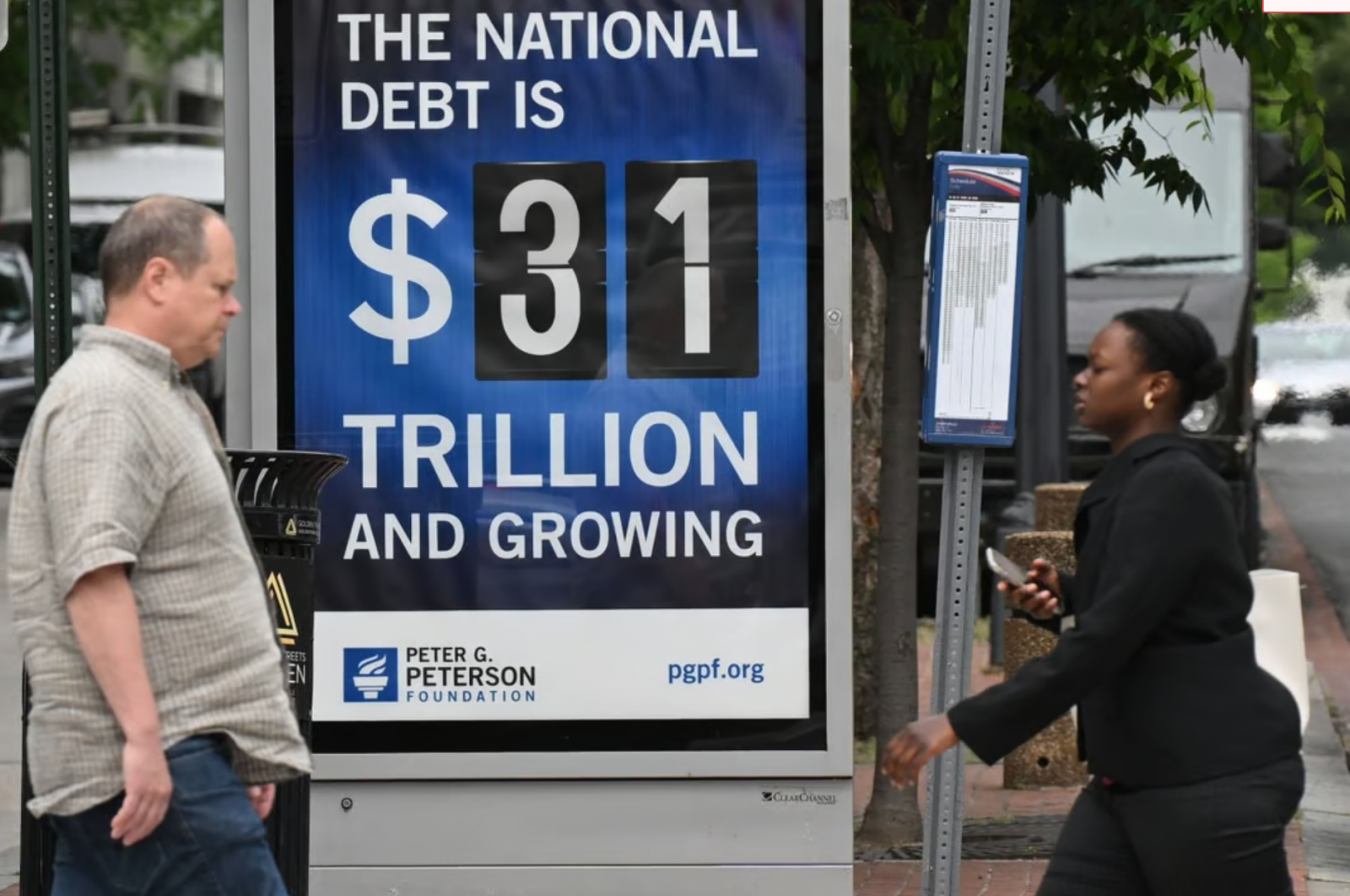 Người đi bộ đi qua một bảng quảng cáo ghi nợ quốc gia ở Washington ngày 19/5. Ảnh: AFP