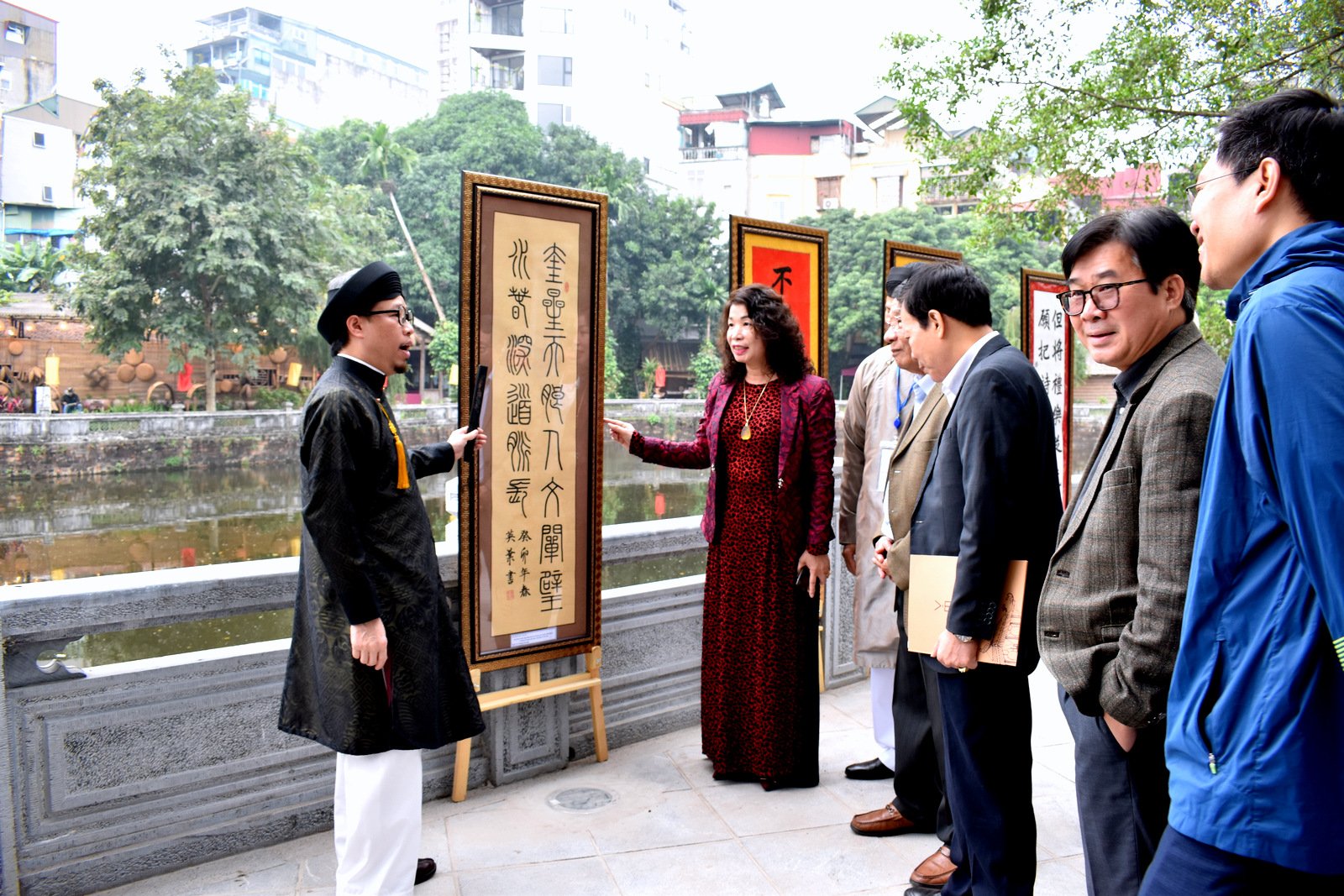 Ông Lê Trung Kiên, Đốc giáo Nhân Mỹ học đường (áo dài đen) đang giới thiệu ý nghĩa của các bức Thư pháp tại gò Kim Châu