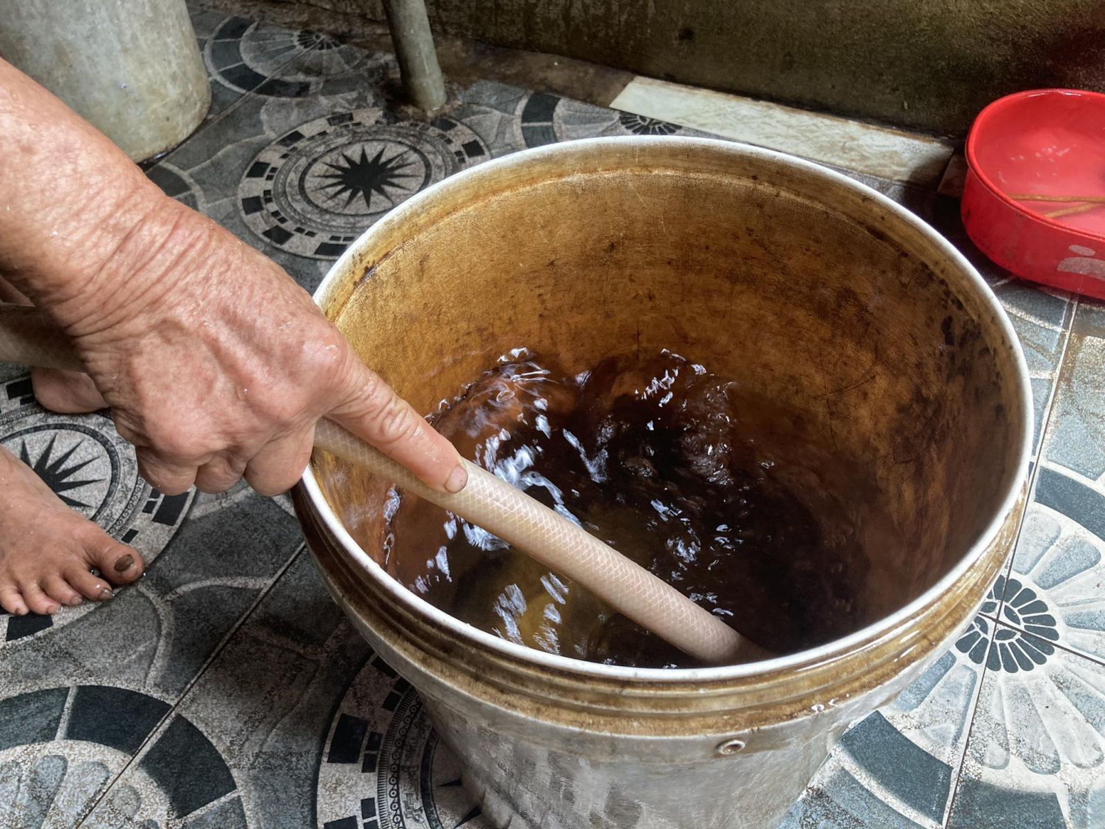 Nguồn nước giếng khoan có mùi tanh, lâu ngày nhuộm vàng thùng đựng nước (Ảnh: Khắc Trà)