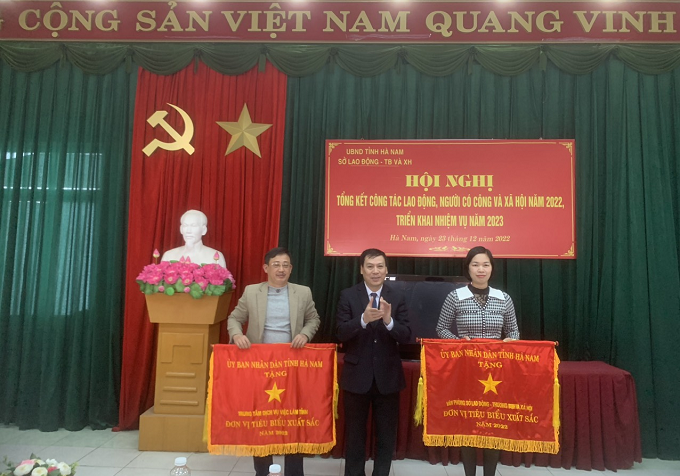 Ông Nguyễn Văn Hảo, Giám đốc Sở LĐ-TB&XH trao Cờ của UBND tỉnh Hà Nam khen thưởng đơn vị đạt kết quả trong công tác năm 2022