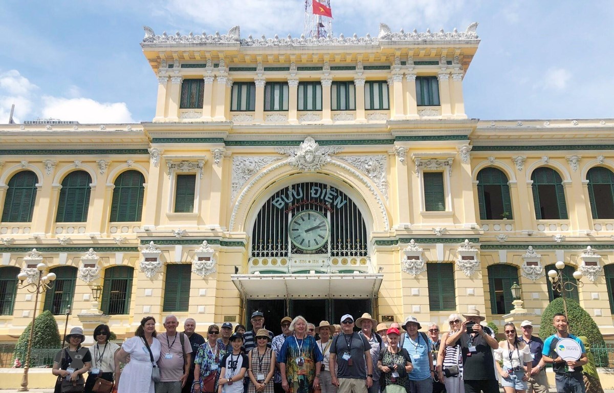 Đoàn khách quốc tế chụp ảnh lưu niệm trước Bưu điện Thành phố Hồ Chí Minh.