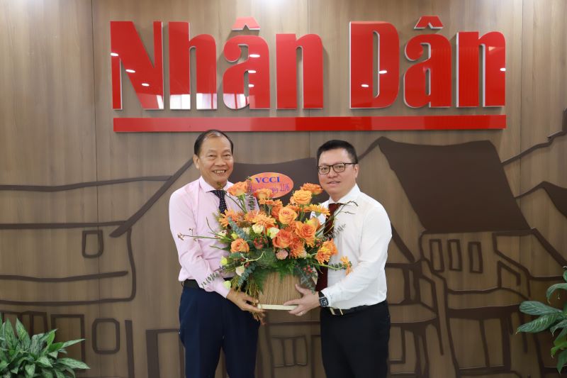 Phó Chủ tịch VCCI Hoàng Quang Phòng tặng hoa cho Tổng Biên tập Báo Nhân dân Lê Quốc Minh